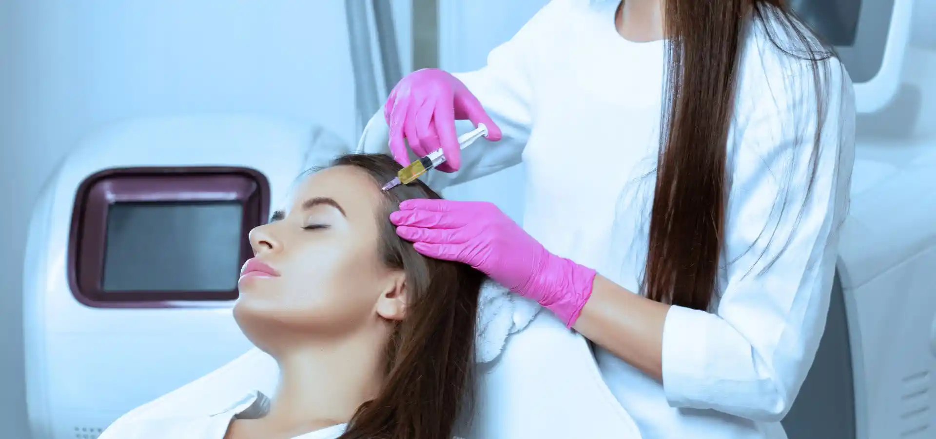 A woman receiving a scalp injection from a professional wearing pink gloves, likely for hair restoration or PRP therapy, while lying back in a clinical chair with her eyes closed.