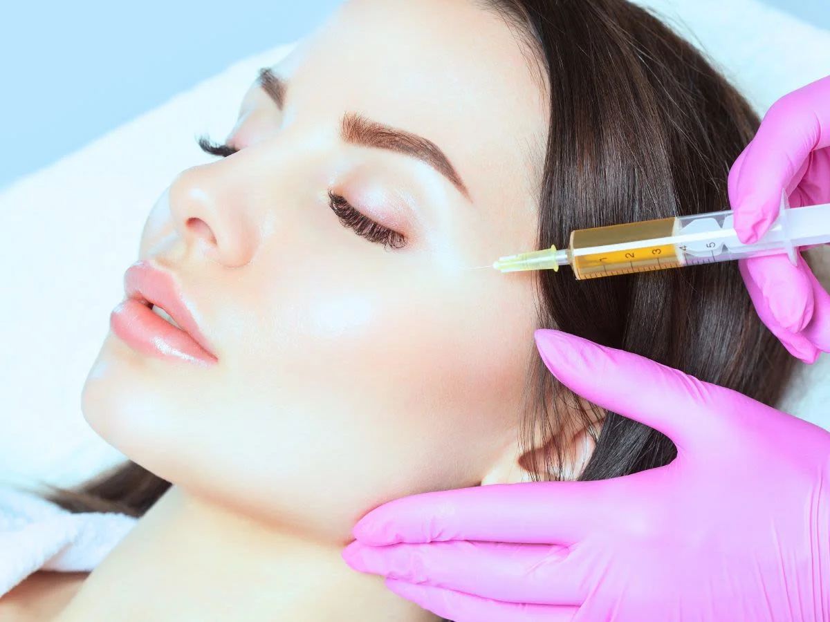 A patient receiving a facial injection treatment at a modern aesthetic clinic, with a practitioner using a syringe for a non-surgical cosmetic procedure.