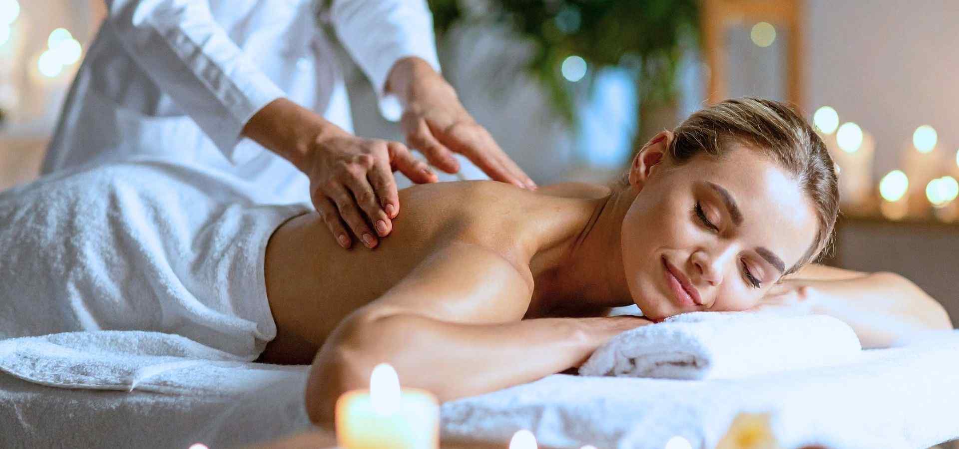 Woman enjoying a relaxing spa massage with soft candlelight and a peaceful wellness atmosphere in a luxury spa setting.