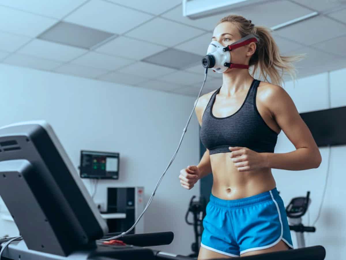Woman running on a treadmill while wearing a VO2 max testing mask during a cardiovascular fitness assessment at a longevity or biohacking clinic.