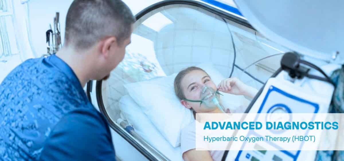 Patient receiving hyperbaric oxygen therapy (HBOT) inside a chamber, wearing an oxygen mask while a clinician monitors the session.