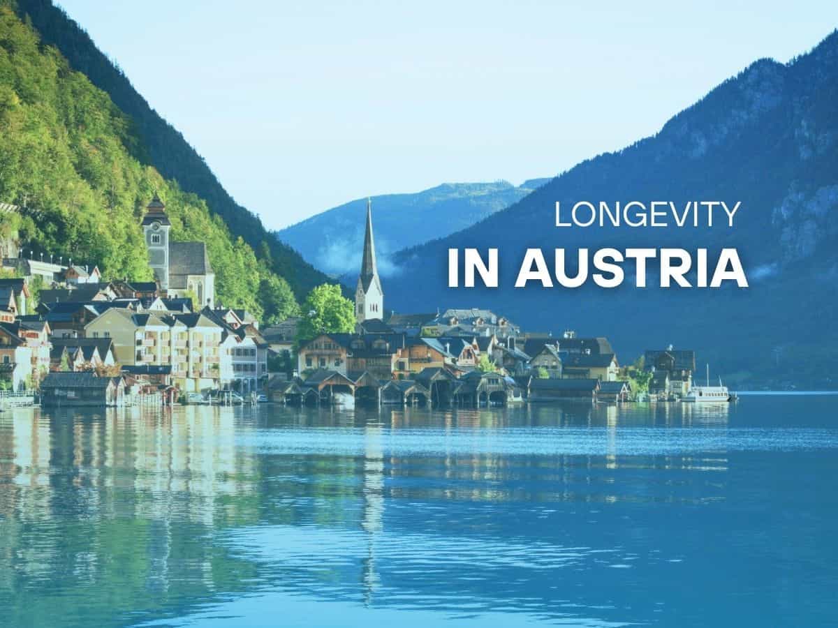 Lakeside alpine village in Austria with mountains and church spire reflected in calm water, with text “Longevity in Austria.”