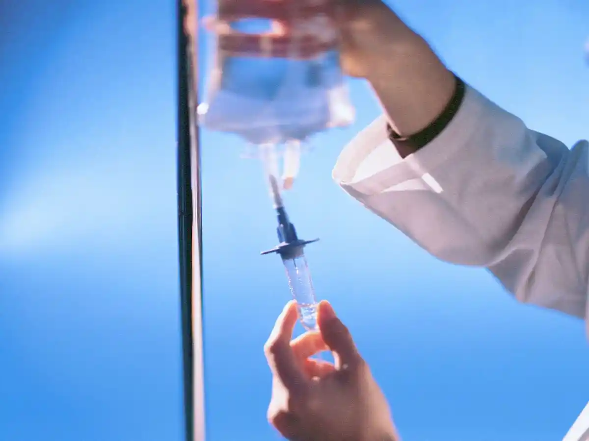Medical professional preparing an IV infusion from a fluid bag.