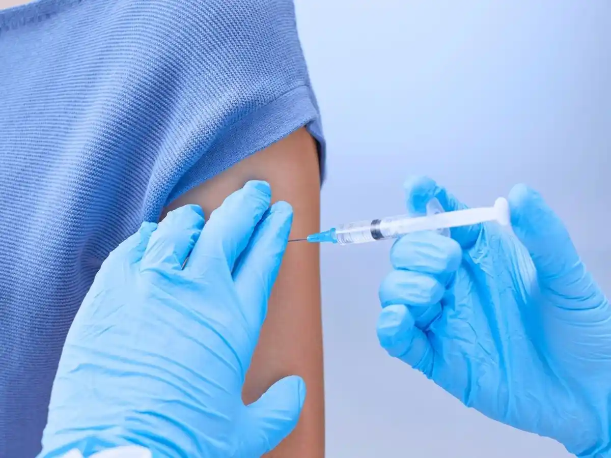 Medical professional administering an injection into a patient’s upper arm.