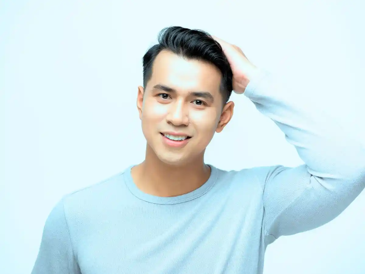 Smiling man touching his hair, illustrating healthy and full hair