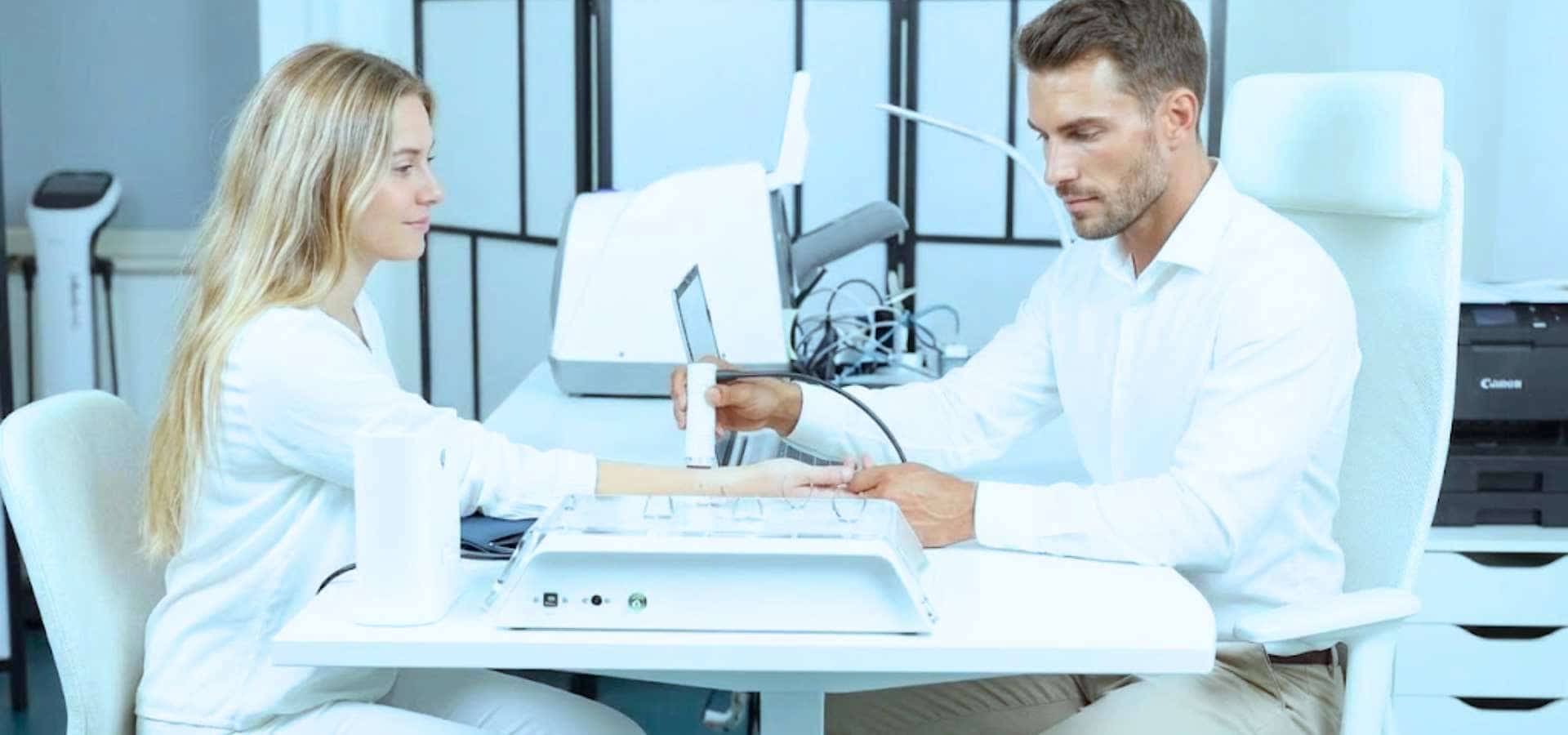 Arzt führt in einer Klinik mit einem medizinischen Gerät einen Handtest bei einer Frau durch.